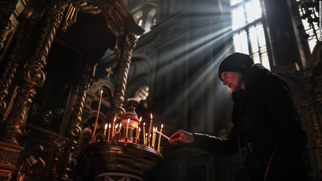 A woman lights a candle during the Sunday service at a monastery in Odesa on March 27.