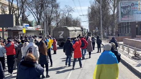 Demonstrators, some displaying Ukrainian flags, chant &quot;go home&quot; as Russian military vehicles reverse course at a pro-Ukraine rally in Kherson on March 20.