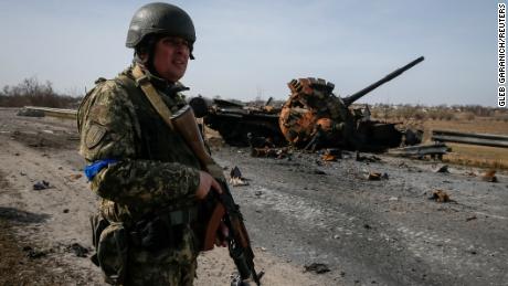 A Ukrainian serviceman stands near the wreck of a Russian tank on the front lines in the Kyiv region, Ukraine on March 28.