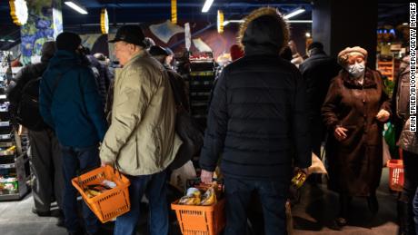 Des résidents qui achètent de la nourriture et des fournitures font la queue à la caisse d'un supermarché à Kiev, en Ukraine, le mardi 1er mars 2022. 