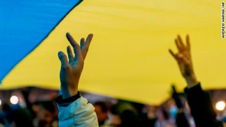 People stand under a giant Ukrainian flag during a vigil to protest the Russian invasion of Ukraine outside the White House on February 24.