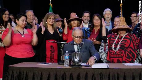 Washington Gov. Jay Inslee, center, signs a bill on Thursday that creates a first statewide alert system for missing Indigenous people.