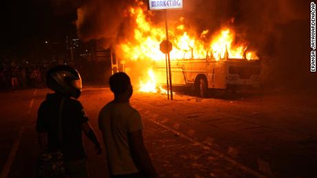 Οι κάτοικοι της Σρι Λάνκα παρακολουθούν ένα φλεγόμενο λεωφορείο κατά τη διάρκεια διαμαρτυρίας έξω από το σπίτι του προέδρου στο Κολόμπο την 1η Απριλίου.