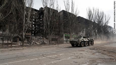 A armored vehicle with pro-Russian troops drives along a street past a residential building destroyed in the besieged southern port city of Mariupol, on March 31, 2022.