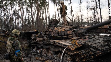 A Ukrainian soldier stands on top of a destroyed Russian tank on the outskirts of Kyiv on March 31, 2022.