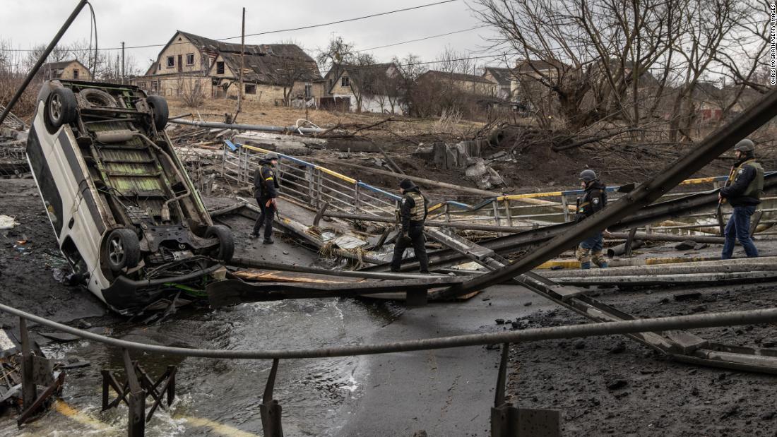 Ukrainian military forces walk across a destroyed bridge in Irpin, Ukraine on Sunday. 