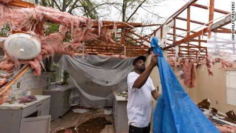Khary Johnson places tarps on the roof of a damaged home after a tornado passed through an area in Allendale, South Carolina, on Tuesday. 