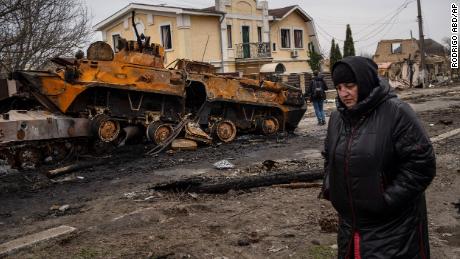 Une femme marche à côté d'un véhicule blindé russe détruit à Bucha le 5 avril.