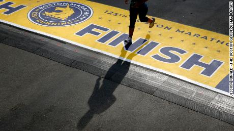A runner casts a shadow as she crosses the finish line of the 125th Boston Marathon in Boston in October. This year, the Boston Marathon will ban runners from Russia and Belarus.