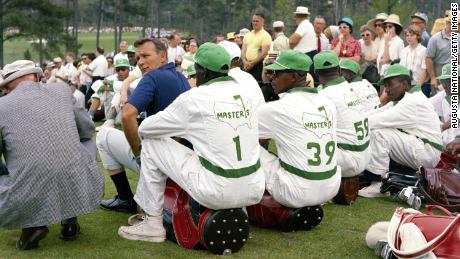 Arnold Palmer looks over his shoulder as he sits with a group of caddies during the 1965 Masters.