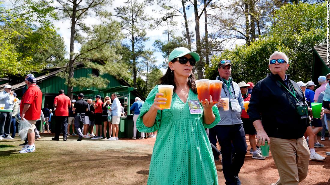 Fans carry beverages near the seventh hole leaderboard on Friday.