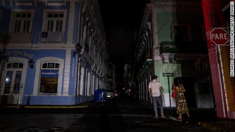 A couple walks on a dark street in San Juan, Puerto Rico, after a major power outage hit the island on April 6, 2022. 