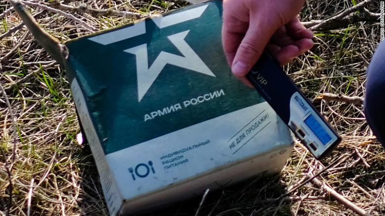 A Ukrainian soldier holds a radiation meter against a Russian military ration pack.