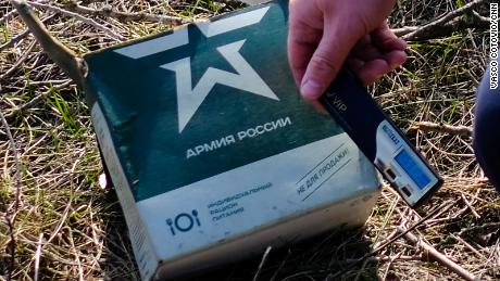 A Ukrainian soldier holds up a radiation meter against a package of Russian military rations.