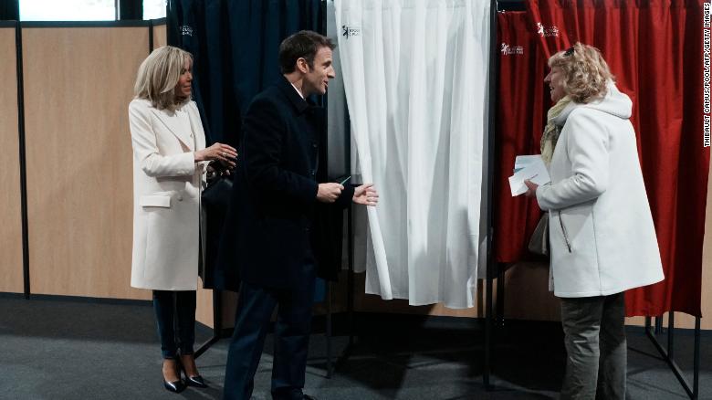 France&#39;s President Emmanuel Macron (center), next to his wife Brigitte Macron (left), speaks to a resident before voting for the first round of the presidential election on Sunday.