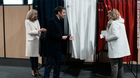 O presidente francês Emmanuel Macron (centro) fala com os moradores antes de votar em sua esposa, Brigitte Macron (à esquerda) no primeiro turno da eleição presidencial de domingo.