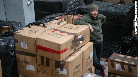 A Ukrainian civil defender standing with boxes of protective equipment provided by UACC after the shipment arrived in a Come Back Alive warehouse in Ukraine.