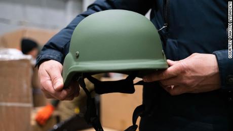 A protective helmet is held by a volunteer for the Come Back Alive foundation in one of its warehouses after a shipment of donations arrived in Ukraine.