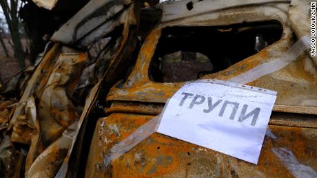 A sign taped to a burned out car reads &quot;corpses&quot; in Ukrainian, telling search teams where to look for bodies.