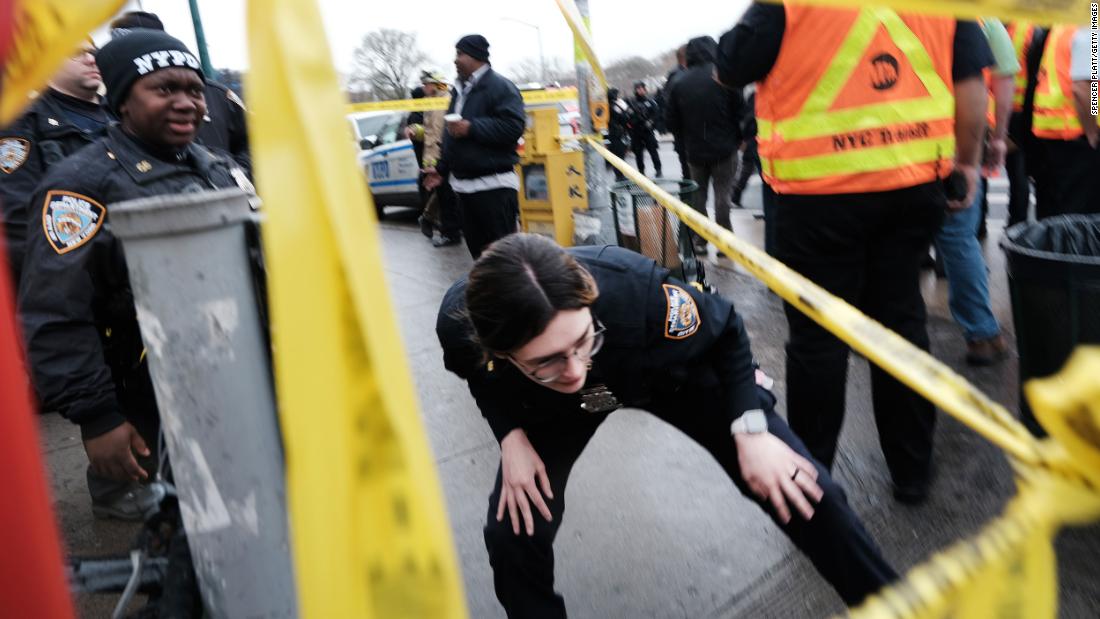 A police officer ducks under police tape at the scene.