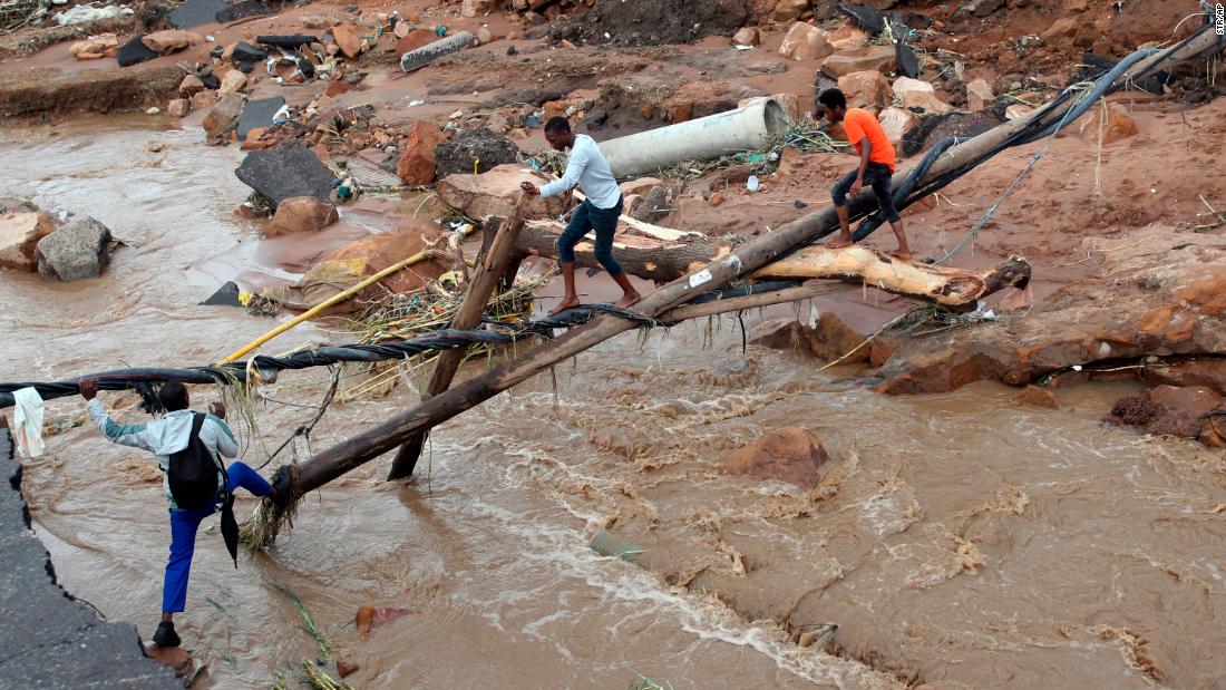 People walk across a makeshift bridge after a bridge was swept away in Ntuzuma, South Africa, on April 12.