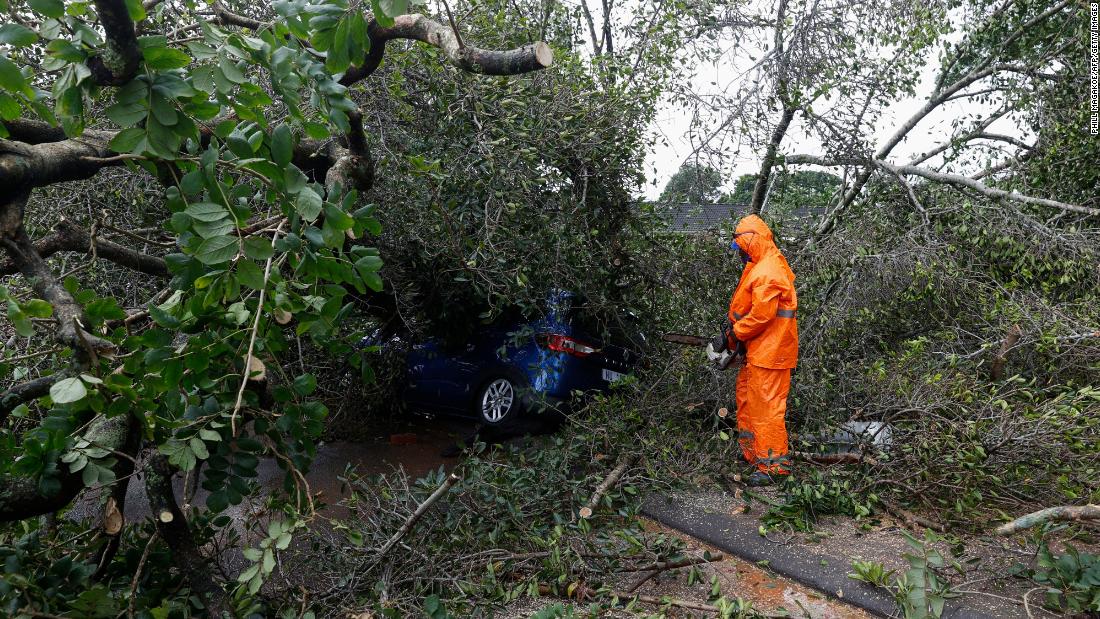 A municipal worker uses a chainsaw to cut branches off a tree that fell onto a car in Pinetown, South Africa, on Tuesday, April 12.