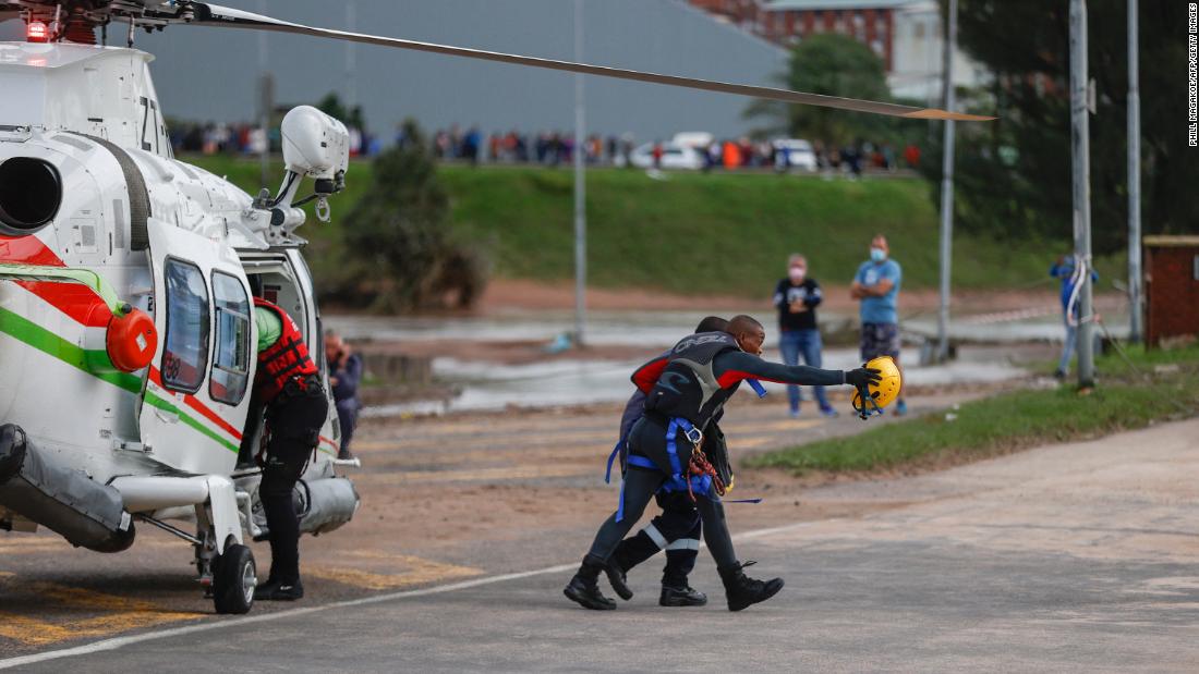 A rescue worker walks with a man who was helped from a flooded workplace near Umlazi, South Africa, on April 12.
