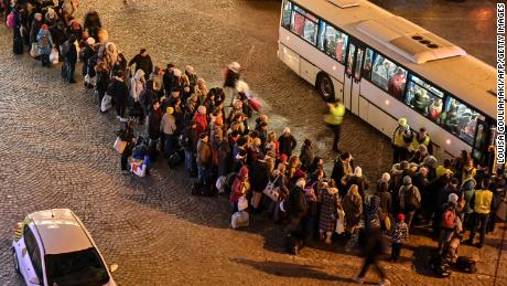 Refugees from Ukraine line up to get on buses to other destinations in Poland, outside the train station in Przemysl, near the Ukrainian-Polish border in southeastern Poland on March 16, 2022.