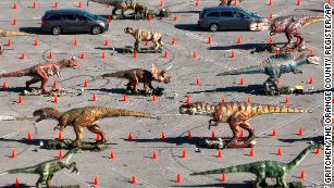 Visitors to Jurassic Empire drive through the dinosaurs in the parking lot of the Westminster Mall in Westminster, Calif., Friday, April 8, 2022. More than 30 animatronic dinosaurs are set up along the east side of the mall. (Jeff Gritchen/The Orange County Register via AP)