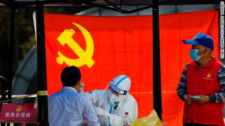 A medical worker tests a resident for Covid-19 in front of the flag of the Communist Party of China on April 12, 2022 in Zhenjiang city in Jiangsu province.