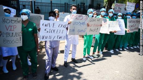 Health workers hold placards during a demonstration against the island&#39;s deepening economic crisis in Colombo on April 6, 2022. 