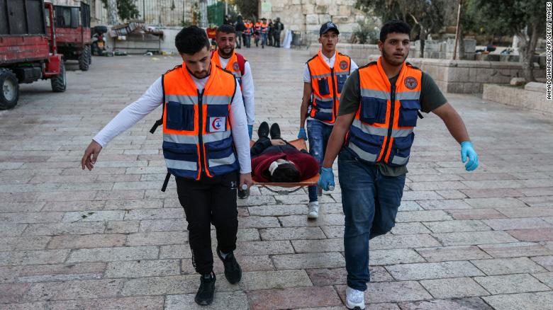 Rescuers evacuate an injured man as Palestinian demonstrators and Israeli police clash at Jerusalem&#39;s al-Aqsa mosque compound on April 15, 2022. 