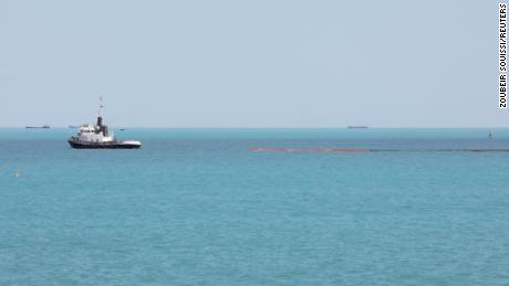 A boat carrying inflatable barriers is seen near the site where a merchant fuel ship sank off the coast of Gabes, Tunisia on April 17, 2022. 