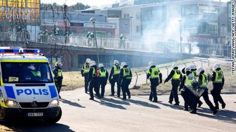 Riot police pass a barricade to enter a shopping center during rioting in Norrköping on Sunday.