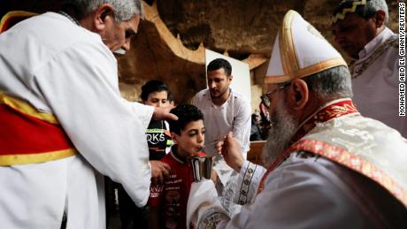 Bir çocuk, 17 Nisan'da Kahire'nin Mokattam Dağı bölgesindeki Samaan al-Kharaz manastırındaki Palm Bazaar'daki bir ayin sırasında Mısırlı bir Kıpti Ortodoks Hıristiyan rahiple yeniden bir araya geldi.