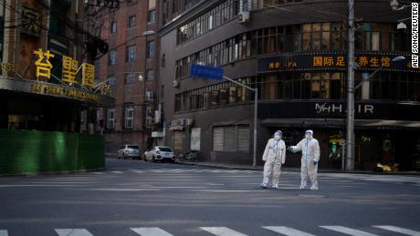 Workers in hazmat suits keep watch on a street during Shanghai's lockdown on April 16.