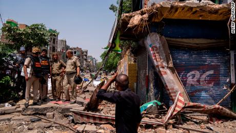 Police officers stand next to a partially demolished shop in the area that saw community violence during a Hindu religious procession on Saturday, in the Jahangirpuri neighborhood of northwest New Delhi, New Delhi, India, Wednesday, April 20, 2022. 