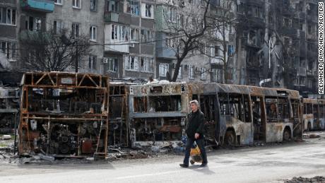 A local resident walks along a street past burnt out buses in Mariupol on April 19, 2022.
