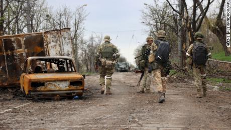 Servicemen of the pro-Russian Donetsk People&#39;s Republic militia walk past damaged vehicles during a heavy fighting in an area controlled by separatist forces in Mariupol.