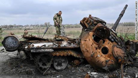 Ukrainian soldiers look at a destroyed Russian tank on a road in the village of Rusanev in the Kyiv region on April 16.