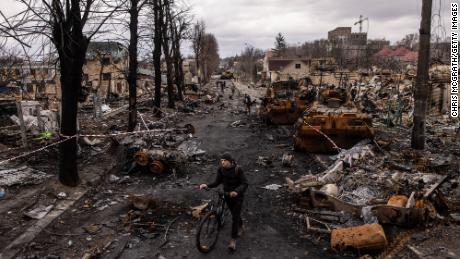 A man pushes his bike through rubble and destroys Russian military equipment on the street April 6, 2022 in Bucha, Ukraine.