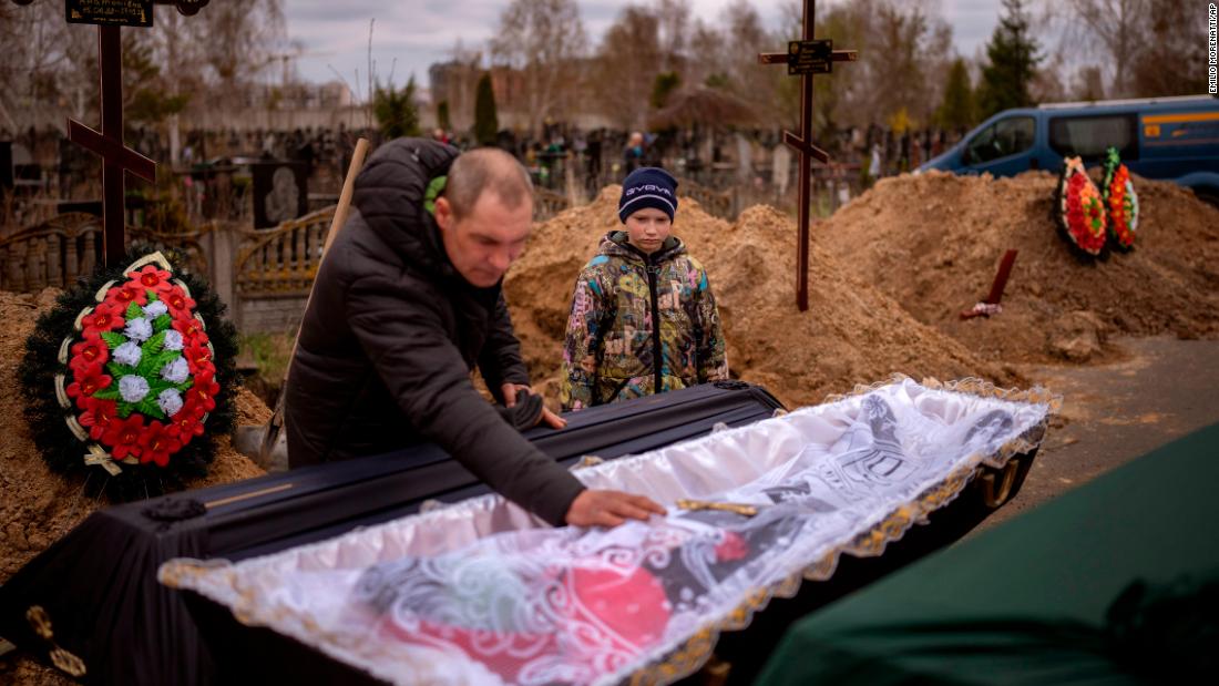 Vova, 10, looks at the body of his mother, Maryna, lying in a coffin as his father, Ivan, prays during her funeral in Bucha on April 20. She died during Russia's occupation of the city, as the family sheltered in a cold basement for more than a month.