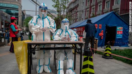 Health workers await a test for residents of Chaoyang District on April 25, 2022 in Beijing, China.