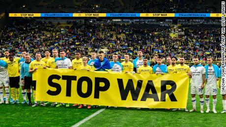 Players of both teams stand behind an anti war banner prior to the friendly fund-raising football match BVB Borussia Dortmund v Dynamo Kyiv in Dortmund, western Germany, on April 26, 2022. - DFL REGULATIONS PROHIBIT ANY USE OF PHOTOGRAPHS AS IMAGE SEQUENCES AND/OR QUASI-VIDEO (Photo by Sascha Schuermann / AFP) / DFL REGULATIONS PROHIBIT ANY USE OF PHOTOGRAPHS AS IMAGE SEQUENCES AND/OR QUASI-VIDEO (Photo by SASCHA SCHUERMANN/AFP via Getty Images)