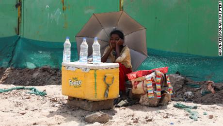 A girl selling water uses an umbrella to protect herself from the sun in New Delhi.