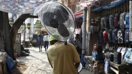 Un uomo porta un ventilatore pedonale in mezzo a un'ondata di caldo a Calcutta, in India.