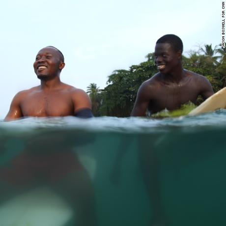Philip Banini and Massalley Comney share a joke in the waters off the coast of Robertsport, Liberia. The seaside community has become popular among surfers, transforming it into an international tourist destination. 