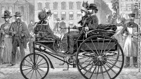 Bertha Benz fuhr in der Kreation ihres Mannes Karl, dem Benz Patent-Motorwagen, herum und nahm Bestellungen von Schaulustigen entgegen.  (Dieser Druck zeigt ein etwas späteres Modell des Patent-Motorwagens, das von einem Mann gefahren wird.)