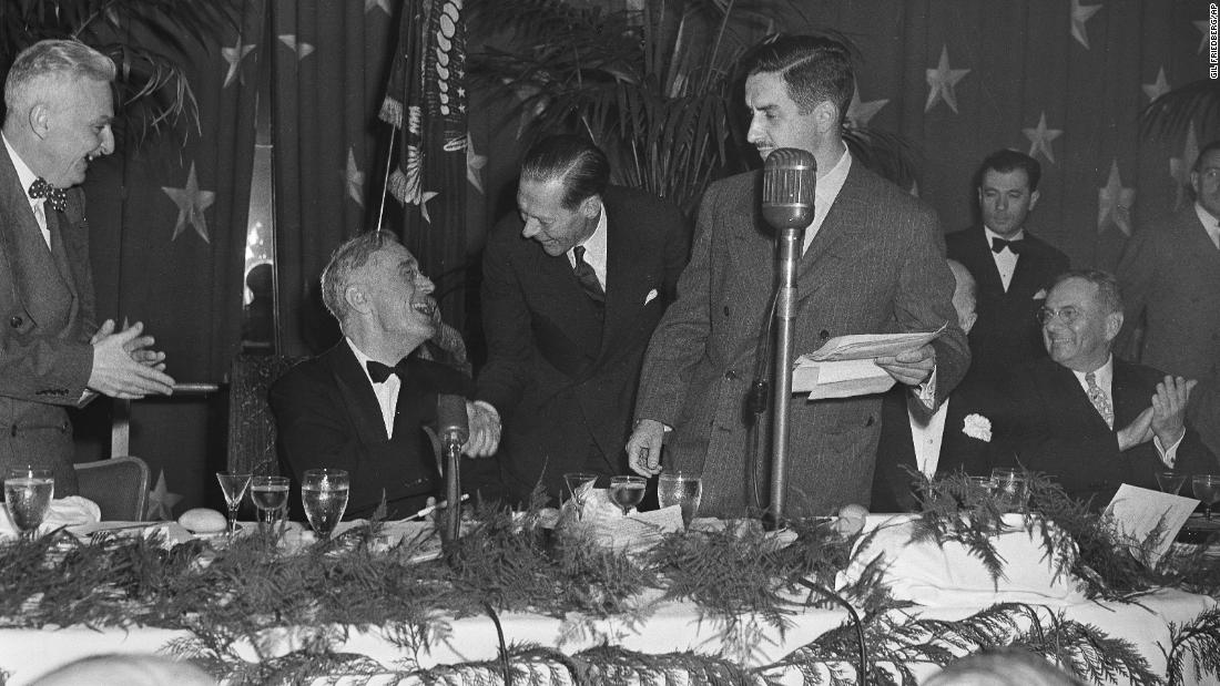 President Franklin D. Roosevelt, seated, shakes hands with Raymond P. Brandt, chief of the Washington bureau of the St. Louis Post-Dispatch, at the 1945 dinner. Roosevelt was congratulating Brandt for winning the first Raymond Clapper Memorial Award, which was given by the White House Correspondents&#39; Association for distinguished reporting.