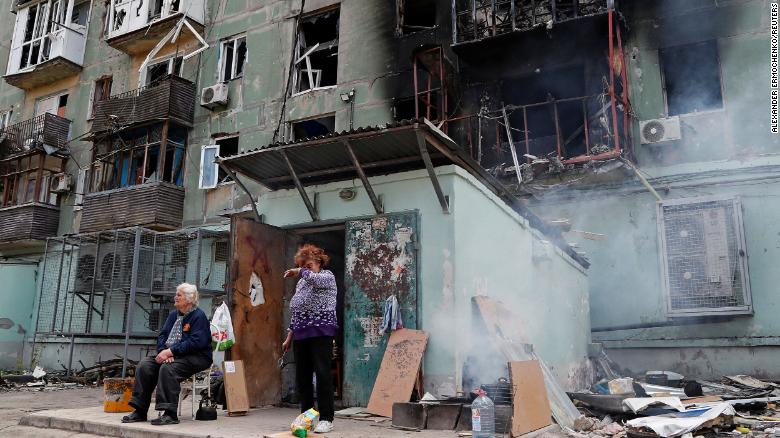 Local residents are seen outside an apartment building damaged in Mariupol on April 28, 2022. 